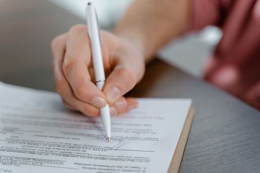 Cum Influențează Scrisoarea de Intenție Aprobarea Contractelor Maritime Internaționale în 2026? 4 Detailed view of a hand writing a signature on an official document with a ballpoint pen.