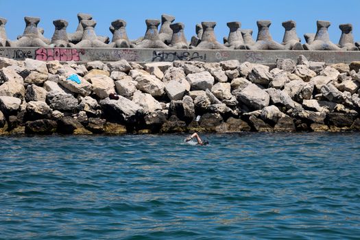 Cum Poți Accesa Cele Mai Atractiv Remunerate Locuri de Muncă pentru Marinari în România, August 2026? 2 A lone swimmer navigates the rocky shoreline of Constanța, Romania, on a sunny day.