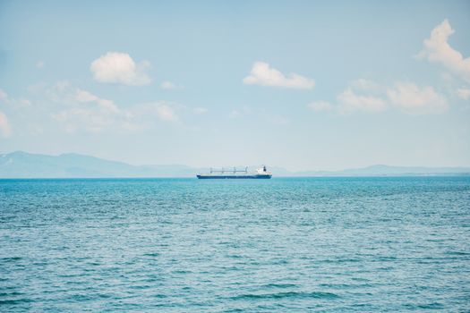 Cum îți influențează certificatul STCW șansele de angajare maritimă în august 2026? 4 A serene view of a cargo ship sailing on a calm ocean with distant mountains and clear sky.