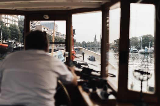 Este Recunoscut un Curs STCW din România pentru Angajarea la Companiile Internaționale în 2026? 2 A helmsman steering a boat through a scenic city canal with visible structures.