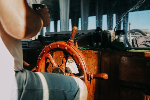 Este Recunoscut un Curs STCW din România pentru Angajarea la Companiile Internaționale în 2026? 3 A man steering a boat using a classic wooden helm in natural daylight.