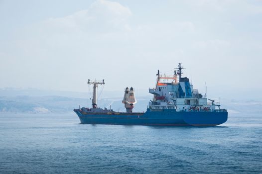 Mituri vs Realitate: De ce Scrisoarea de Intenție nu este Doar un Formalism în Cariera Maritimă 2 A large blue cargo container ship sails across the calm sea under a clear sky, symbolizing global trade.