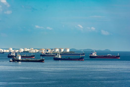 Mituri vs Realitate: De ce Scrisoarea de Intenție nu este Doar un Formalism în Cariera Maritimă 4 A fleet of cargo ships docked near oil storage tanks along a serene coastline with a clear blue sky above.