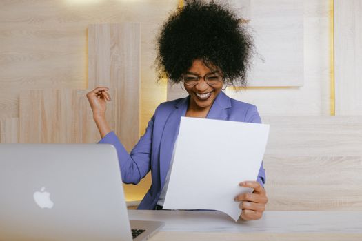Scrisoarea de Intenție vs Cerințele pentru Angajare: Ce Contează Mai Mult în Cariera Maritimă? 3 A cheerful woman celebrates her success at work, looking at a document in an office setting.
