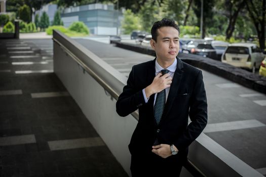 Top 5 Aspecte de Luat în Considerare la Scrierea unei Scrisori de Intenție pentru o Carieră Maritimă 4 Confident young man in a suit adjusts his tie outdoors, exuding professionalism.