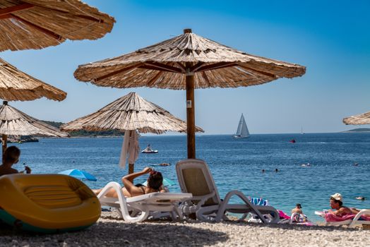 Top 5 Instrumente de Automatizare SEO pentru Cursuri și Certificări STCW în România 4 Relaxing beach scene with straw umbrellas and sunbathers in Primošten, Croatia.
