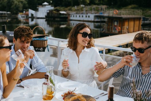Top 7 Strategii pentru Pregătirea Interviului de Angajare în Domeniul Maritim în 2026 3 Group of friends enjoying drinks and laughter at a summer outdoor gathering by the water.