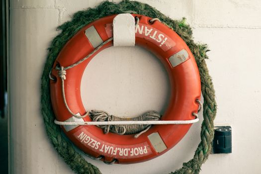 Rustic lifebuoy on a white wall, showcasing nautical decor and maritime theme.