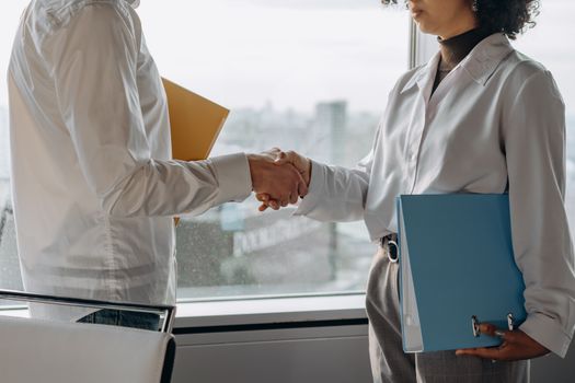 Top 6 Impacturi ale Epavei Avantis III asupra Certificării STCW și Angajării Navigatorilor 2 Two professionals in business attire shaking hands in an office setting with view.