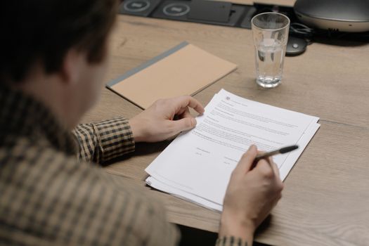 Top 6 Impacturi ale Epavei Avantis III asupra Certificării STCW și Angajării Navigatorilor 4 A businessman is reviewing a contract while holding a pen at a desk with a glass of water nearby.