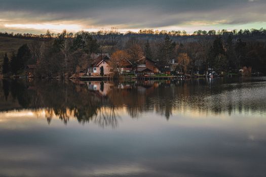 Captivating view of a serene village by a reflective lake in autumn, Romania.
